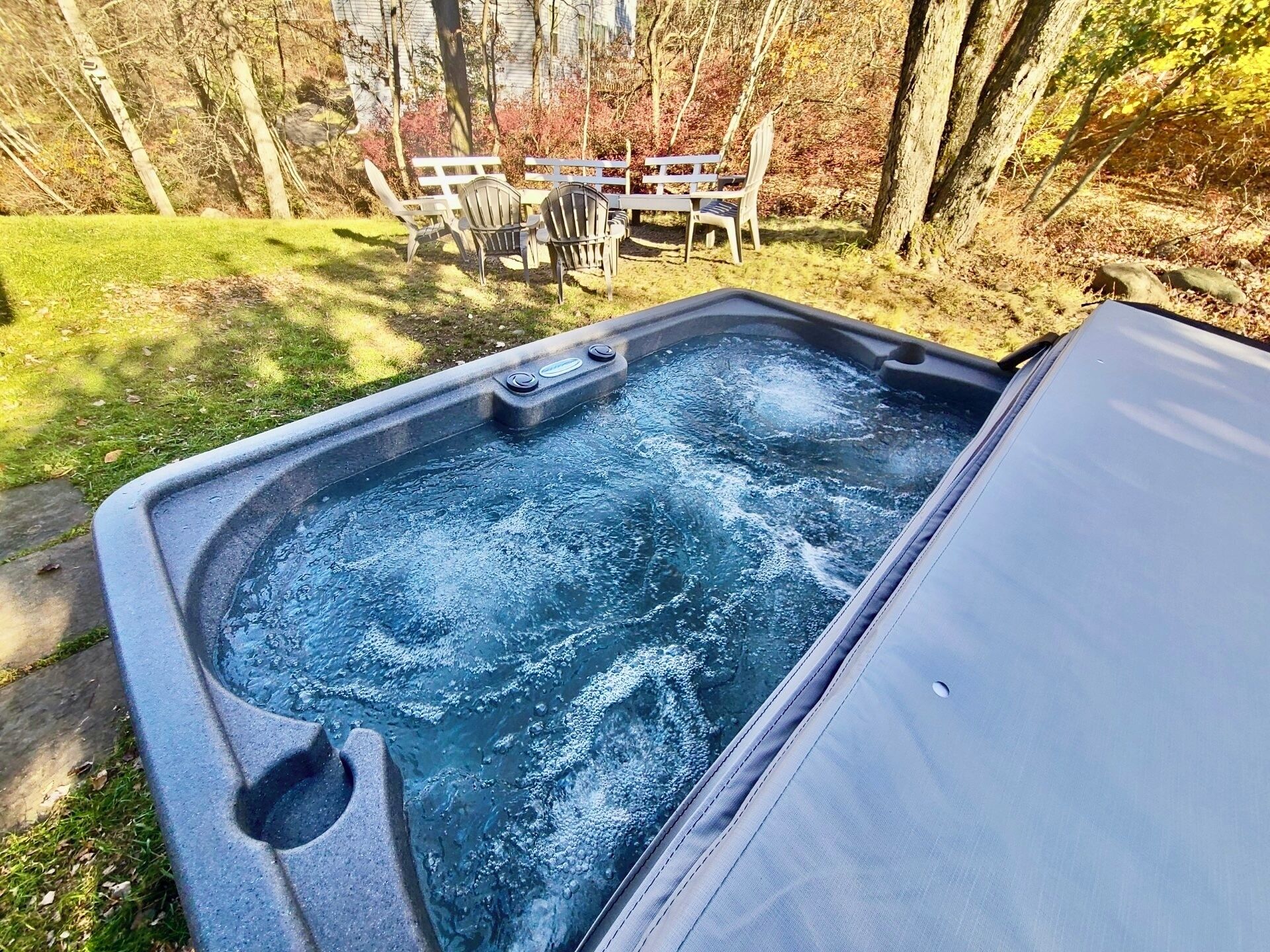 Una vasca idromassaggio con un pontile in legno e sedie sullo sfondo.