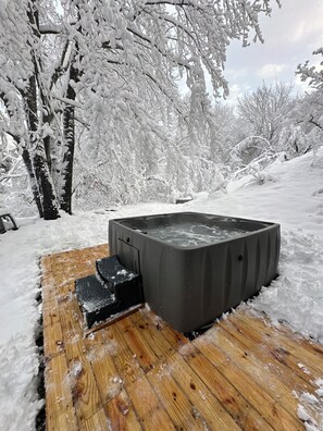 A hot tub on a wooden deck surrounded by snow-covered trees. - Big Blue Lake House Complete with Game Room & Hot Tub (Long Pond)