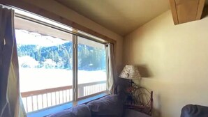 A room with a large window, a sofa, and a lamp. - 4K River Ranch • Condo 3 (sleeps 4) (Red River)
