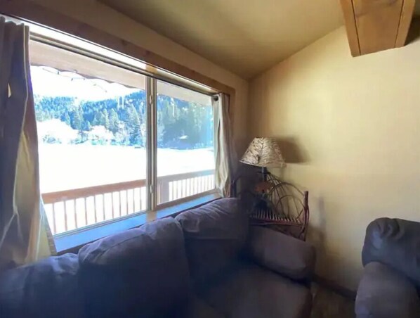 A room with a large window, a sofa, and a lamp.