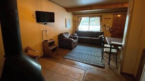 Uma sala de estar aconchegante com lareira, sofá, TV fixada na parede e um espaço de jantar com mesa e cadeiras.