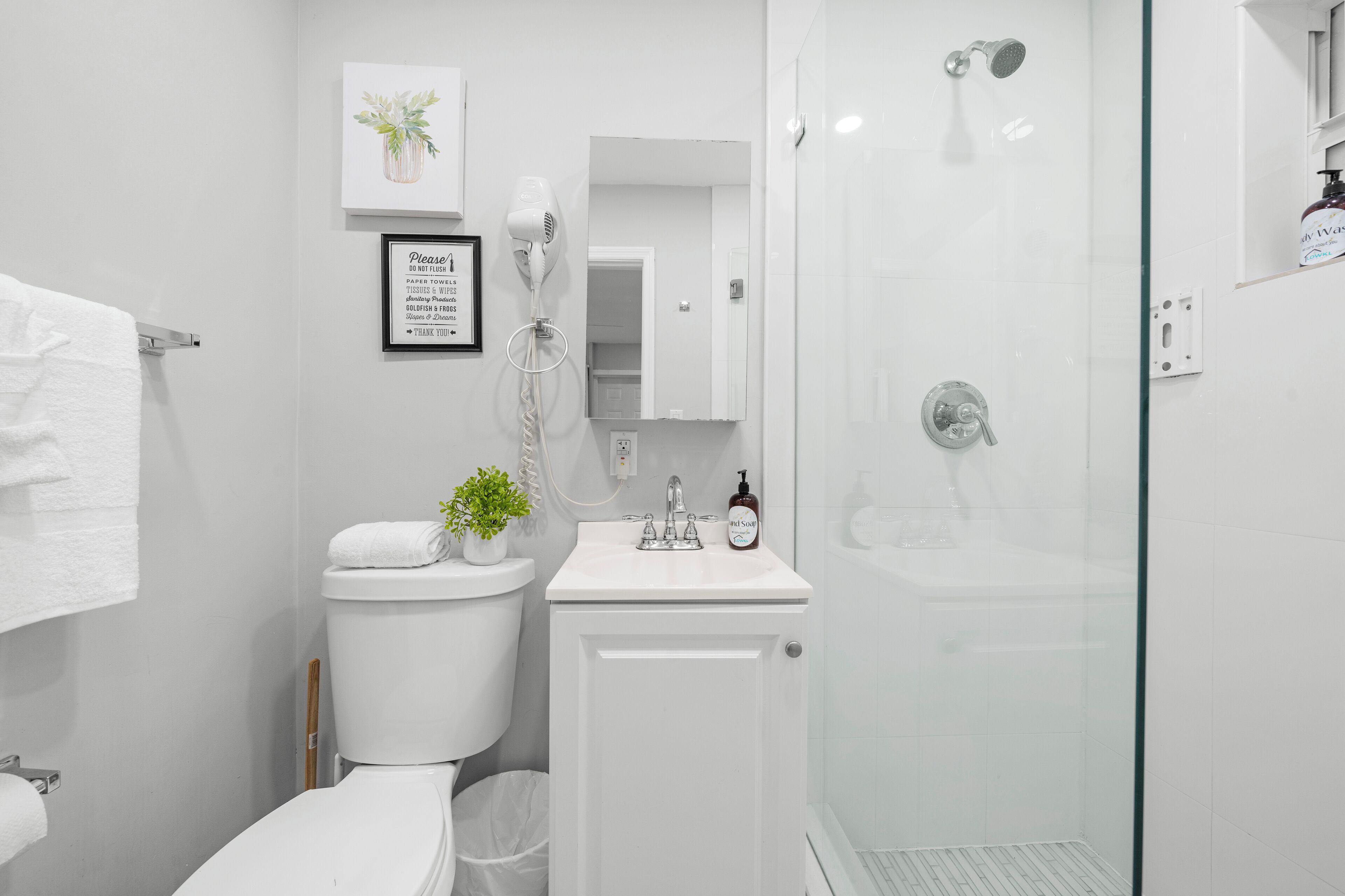 Une salle de bain moderne équipée de toilettes, d’un lavabo et d’une douche à parois en verre.