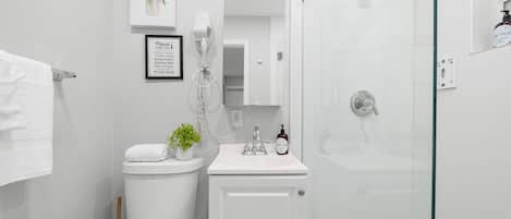 A modern bathroom with a toilet, sink, and glass shower enclosure.