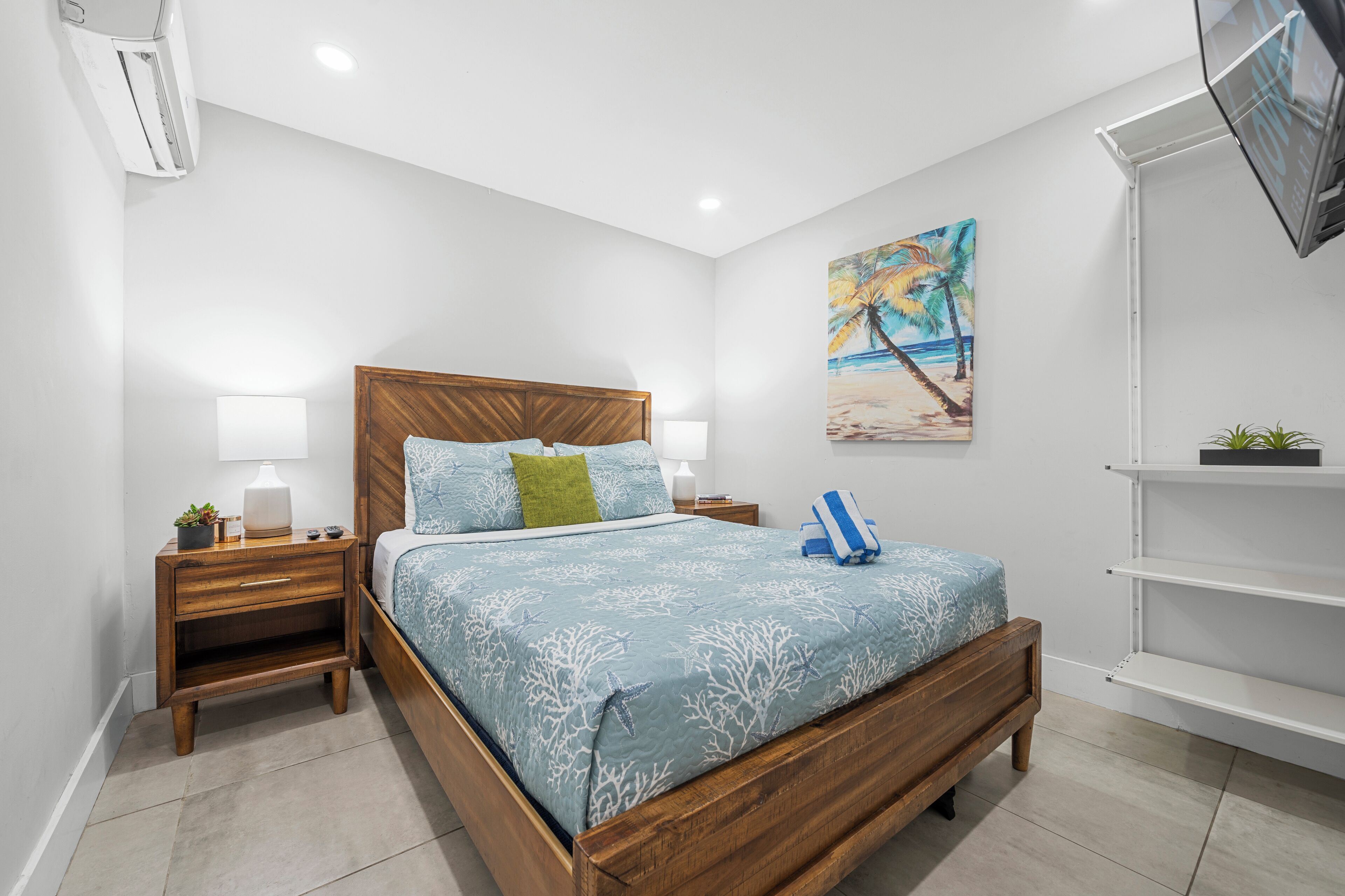 A bedroom with a wooden bed, nightstands, a painting, and a TV on a stand.