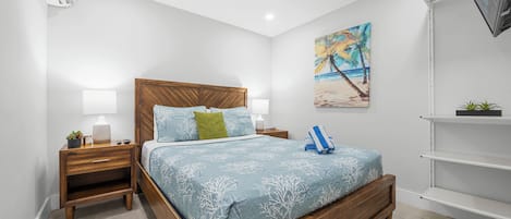 A bedroom with a wooden bed, nightstands, a painting, and a TV on a stand.