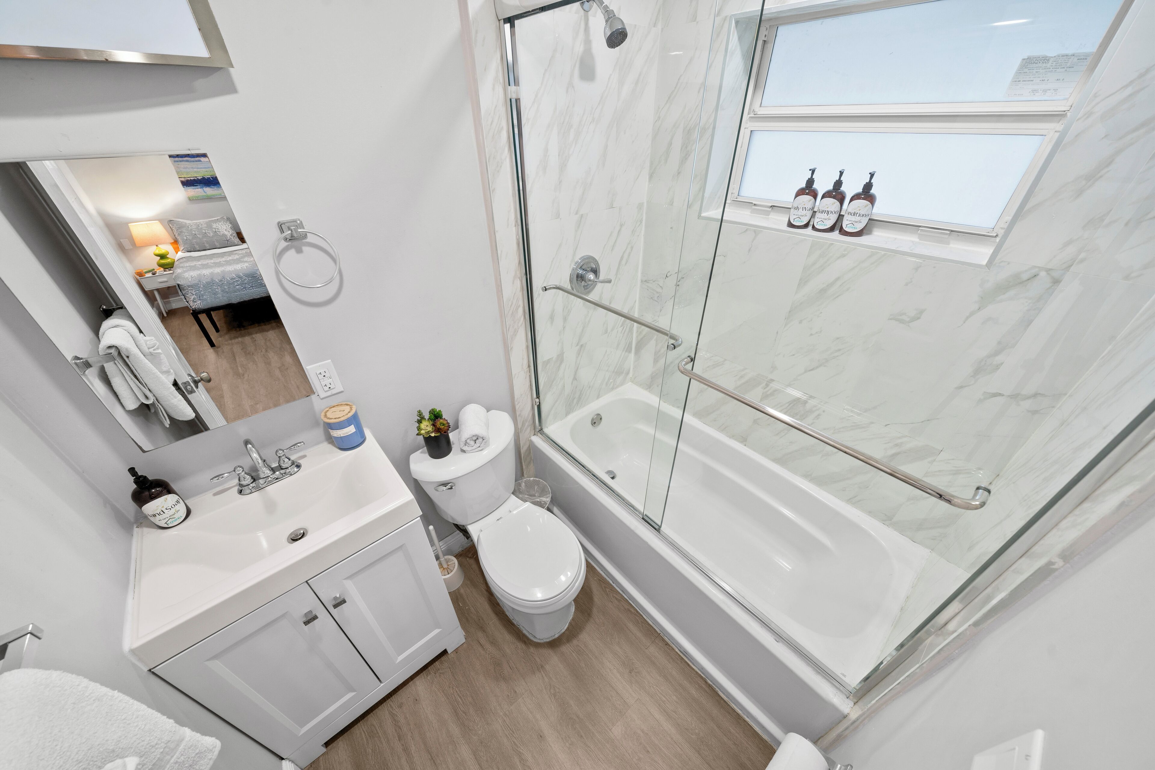 A modern bathroom with a glass-enclosed shower, a white sink, and a toilet.