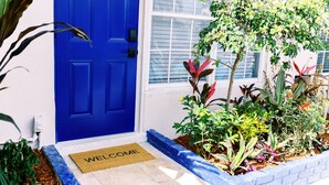 A blue door with a welcome mat, surrounded by a variety of plants and a brick border. - Casa Cordova by Lowkl (Fort Lauderdale)