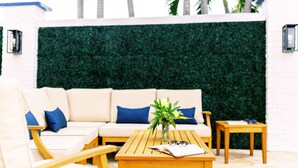A modern outdoor seating area with a sofa, wooden tables, and a decorative plant. - Casa Cordova by Lowkl (Fort Lauderdale)