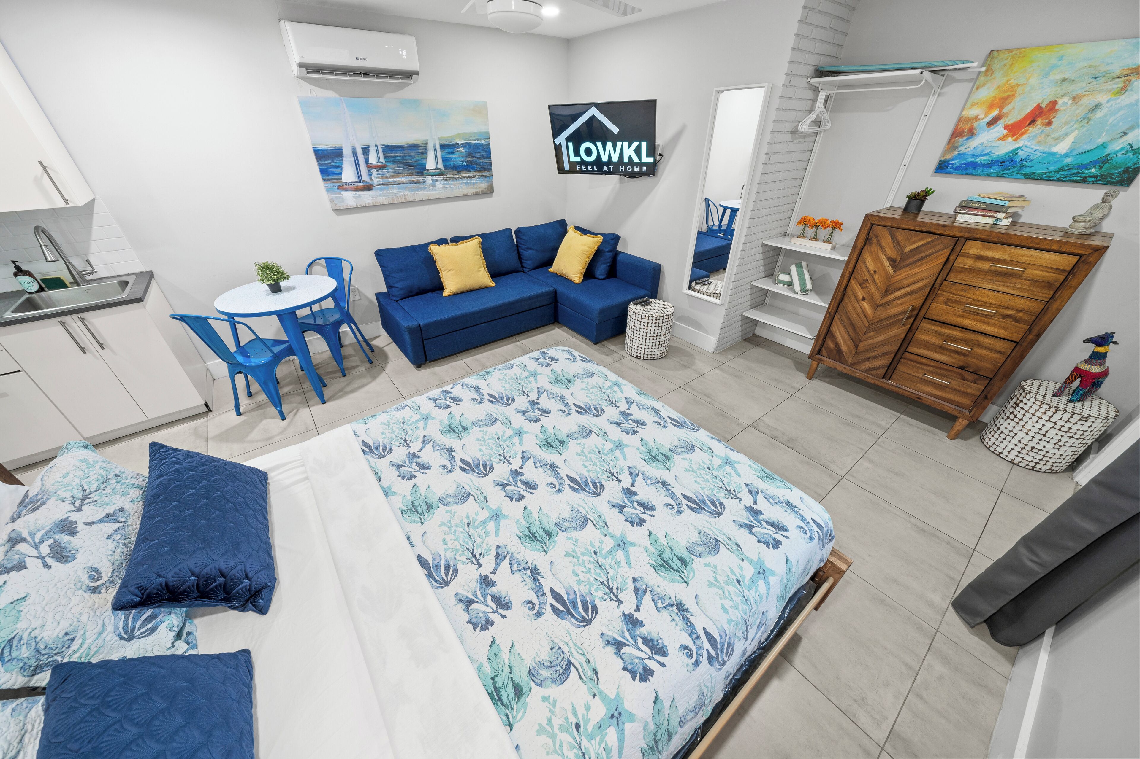 Habitació d'hotel moderna amb un llit, un sofà, una taula de menjador i una zona de cuina.