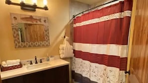 Une salle de bain avec un lavabo, un miroir et un rideau de douche à motifs.