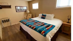 Une chambre à coucher avec un grand lit, une table de chevet, une lampe, une fenêtre, une chaise et un porte-serviettes.