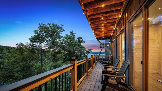 A wooden deck with a railing overlooking a forested area. - NEW Luxury Cabin, Lake and Mountain Views/ Easy Access to Pigeon Forge! (Sevierville)