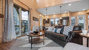 A cozy cabin interior with a wooden interior, a sofa, a coffee table, and a kitchen area. - NEW Luxury Cabin, Lake and Mountain Views/ Easy Access to Pigeon Forge! (Sevierville)