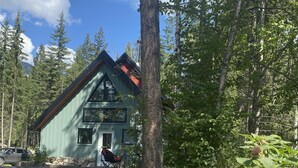 Una cabaña de techo inclinado, rodeada de un bosque.