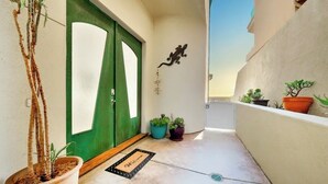 A narrow hallway with a green door, potted plants, and a welcome mat. - Ultimate Paradise Retreat  (Oceanside)