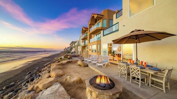 A beachfront property with a fire pit, outdoor seating, and a view of the ocean. - Ultimate Paradise Retreat  (Oceanside)