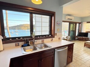 A kitchen with a large window, a sink, and a view of boats on the water.
