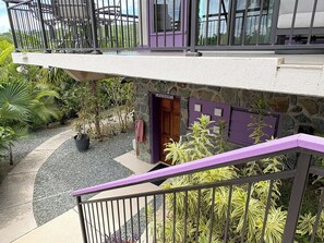 A multi-level building with a stone facade, a purple door labeled 'laundry,' and a balcony with a railing.