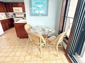 A kitchen with a dining area, including wicker chairs, a glass table, and a framed picture on the wall. - This exceptional property offers the convenience of being just a short stroll from Cruz Bay, all while providing the comfort of full air conditioning. Don't miss out on this perfect blend of location and luxury! (St John)
