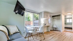 Un espace de vie compact comprenant un canapé, une table à manger, des chaises et un coin cuisine.