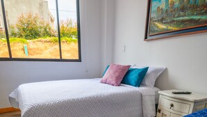 A bedroom with a bed, a nightstand, a window, and a painting on the wall. - El Roble Hotel Boutique (Paipa)