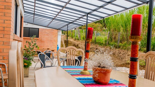 An outdoor patio with a table set for dining, surrounded by chairs, and a potted plant. - El Roble Hotel Boutique (Paipa)