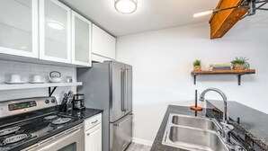 Une cuisine moderne avec des armoires blanches, des appareils en acier inoxydable, un comptoir en granit et un four encastré.