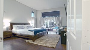 Een slaapkamer met een houten bed, een nachtkastje, een groot raam en uitzicht op een buitenruimte.