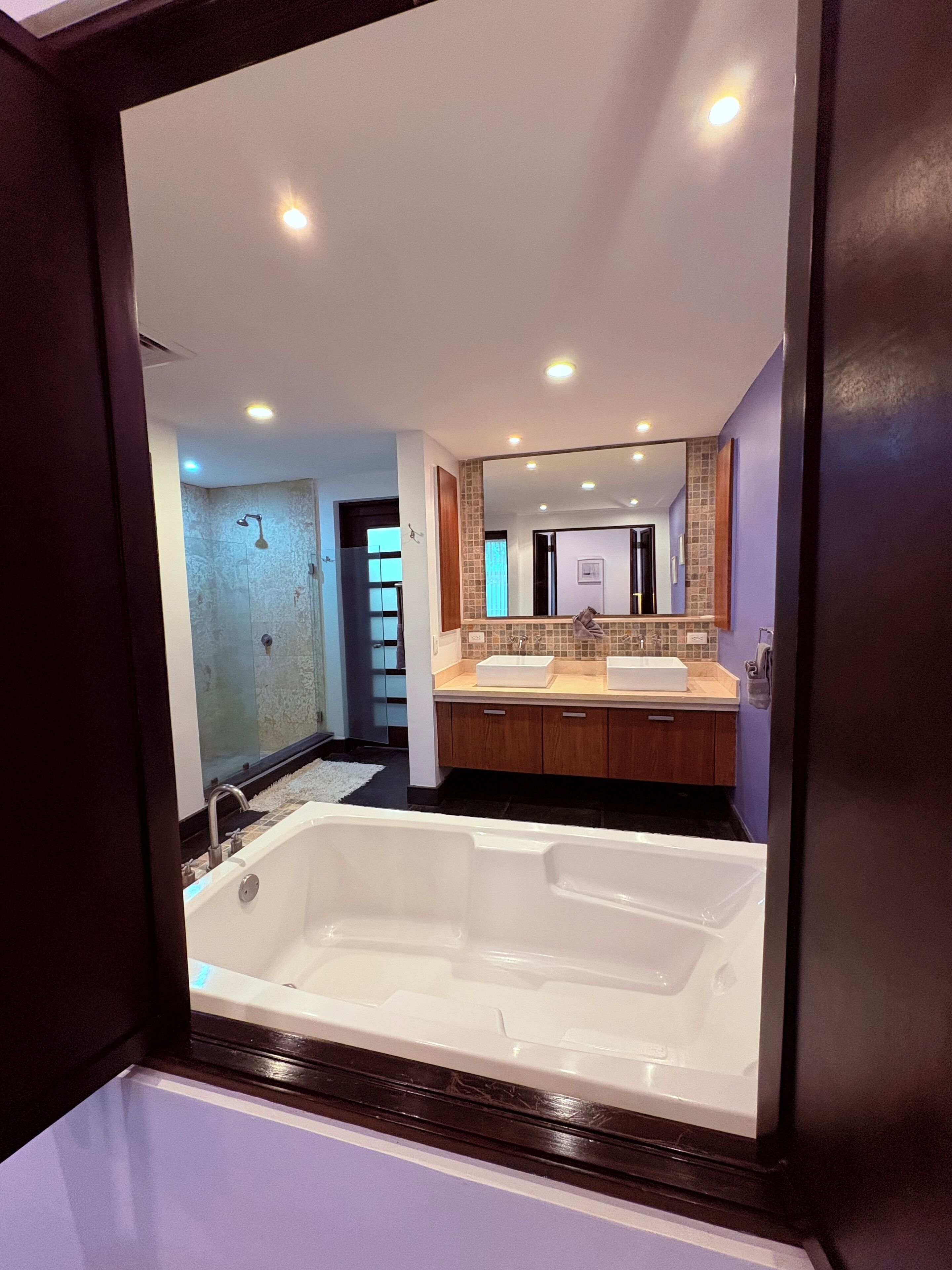 A modern bathroom with a large bathtub, two sinks, and a mirror.