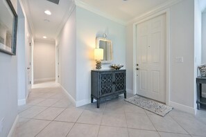 Enter a serene space with a console table, mirror, and decorative bowl, set against a light blue backdrop and complemented by a small rug.