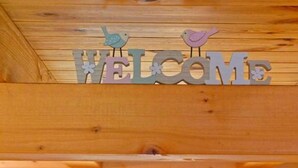 A wooden interior with a 'WELCOME' sign above a window, flanked by plaid curtains. - Lavanda Land - Villa Tanya Mrežnica (Duga Resa)