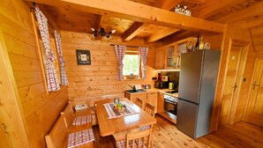 A cozy cabin-style kitchen with wooden walls, a dining table with benches, and a refrigerator. - Lavanda Land - Villa Tanya Mrežnica (Duga Resa)