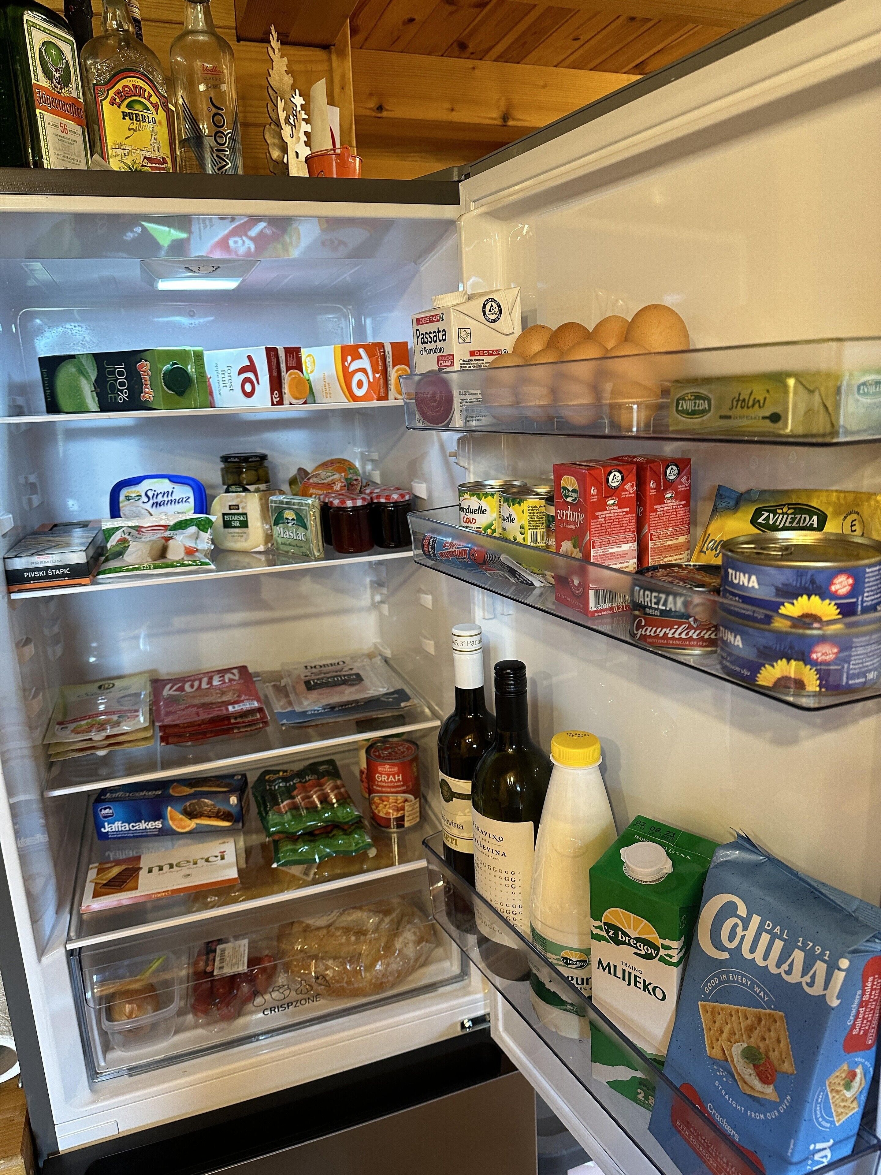 A refrigerator stocked with various food items and beverages, including bottles, cans, and packaged goods.