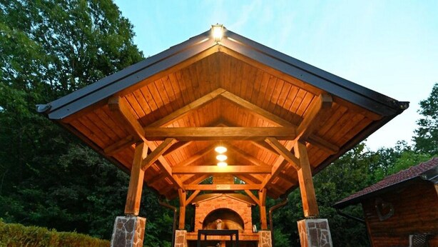 A covered outdoor seating area with stone pillars and a wooden roof, surrounded by greenery. - Lavanda Land - Villa Tanya Mrežnica (Duga Resa)