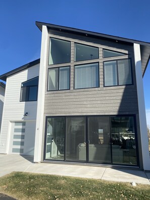 A modern two-story house with large windows, a garage, and a well-maintained lawn.