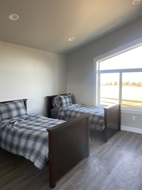 A bedroom with two beds, a large window, and a ceiling light.