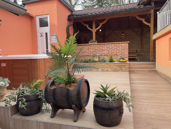 A courtyard with a wooden bench, a brick wall, and potted plants. - Holiday Home Grofica (Daruvar)