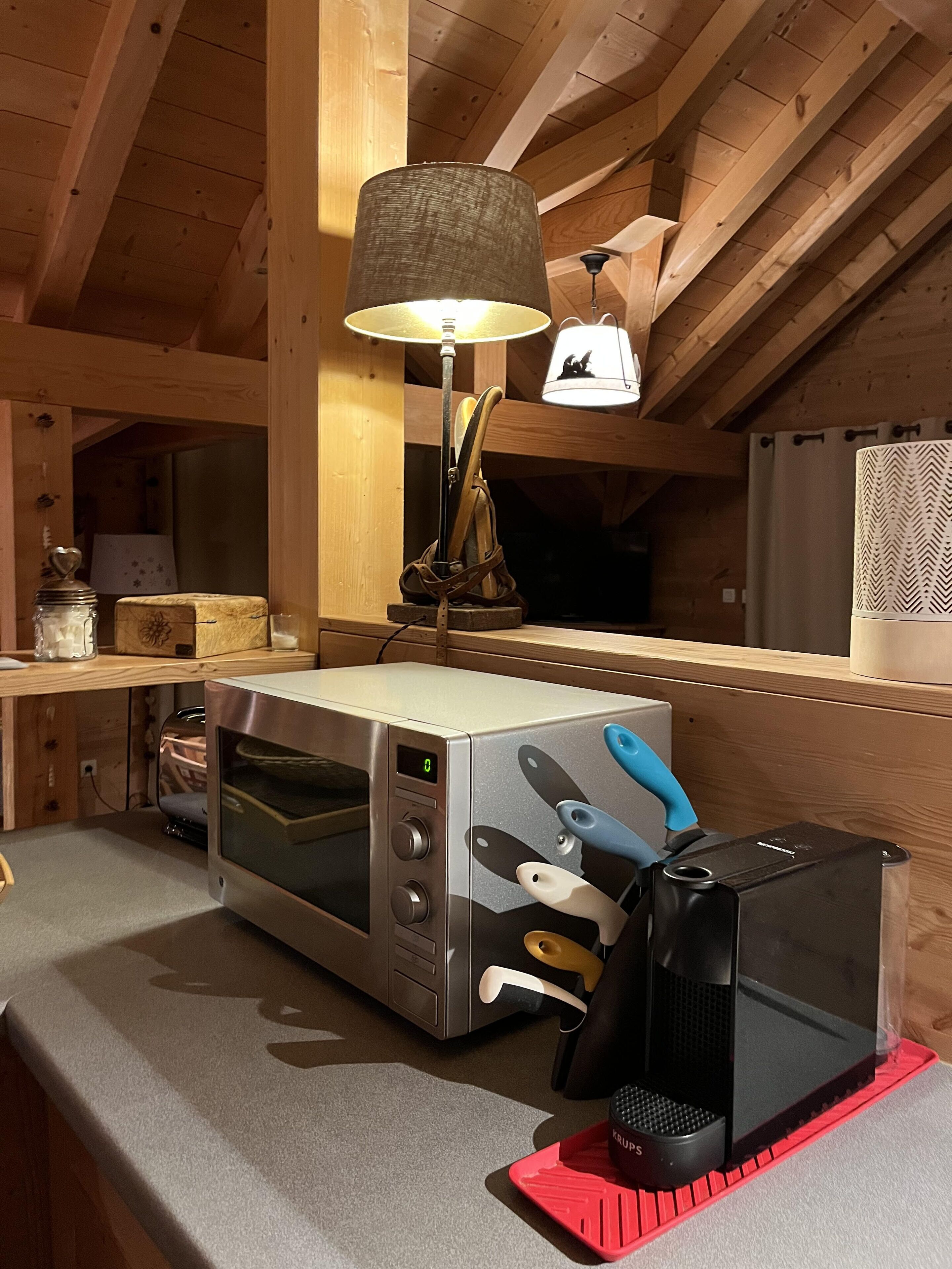 A kitchen with a microwave, toaster, and kettle on a wooden countertop.