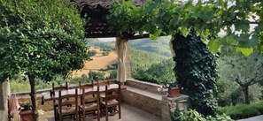 A wooden table and chairs under a pergola with a view of a valley. - La finestra sull'Umbria - countryhouse with private pool with beautiful views (Carpini, Perugia)