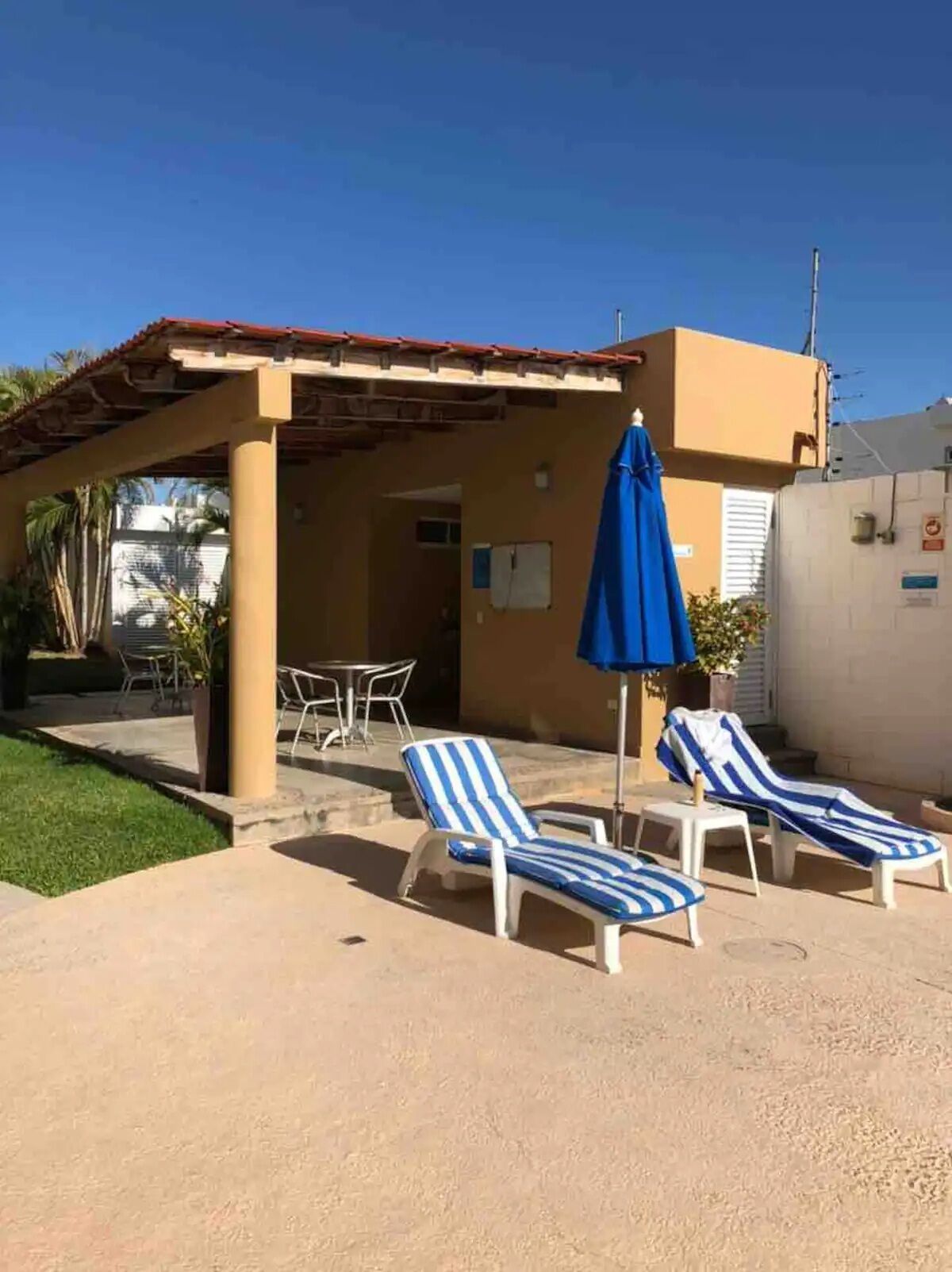 Un edificio con un patio cubierto, asientos exteriores y sillones de descanso.
