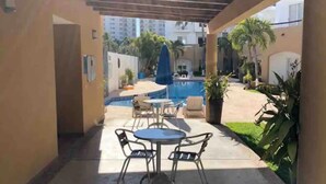 Un patio techado con piscina, asientos al aire libre y plantas en macetas.