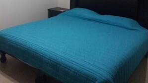 Un dormitorio con una cama individual, cabecera negra y una mesita de noche pequeña.