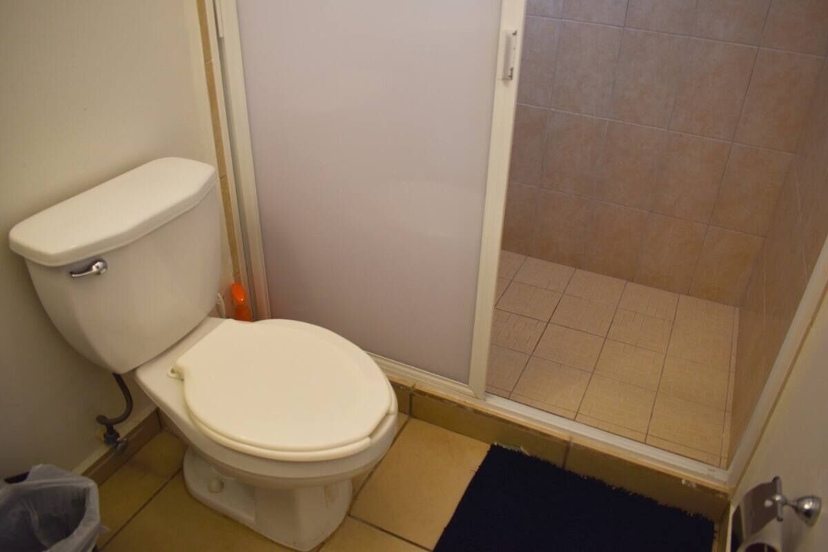 Un bagno piccolo con il water, una zona doccia e un pavimento piastrellato.