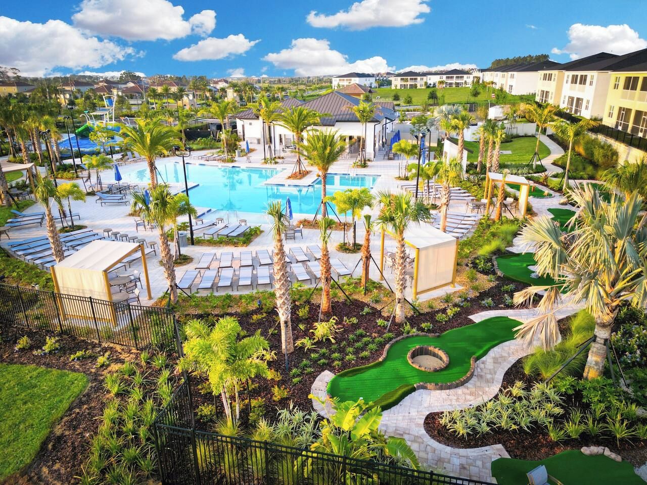A resort with a swimming pool, palm trees, and a golf course.
