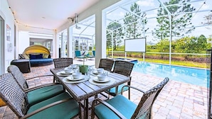 Eine Außenpatio mit Pool, Korbmöbeln und einem großen Fenster mit Blick auf einen Garten.