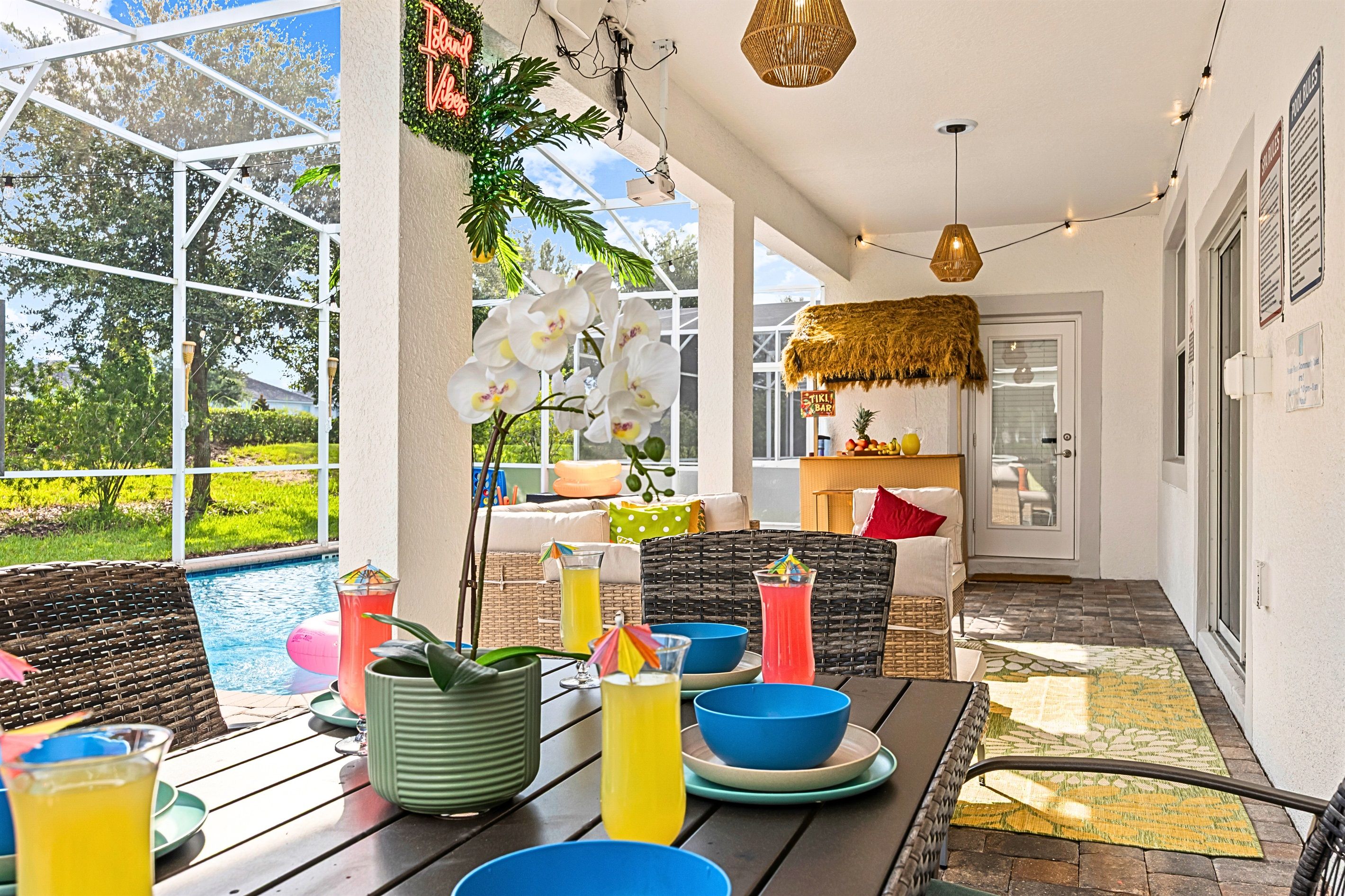 An outdoor patio area with a pool, wicker furniture, and a thatched roof structure.