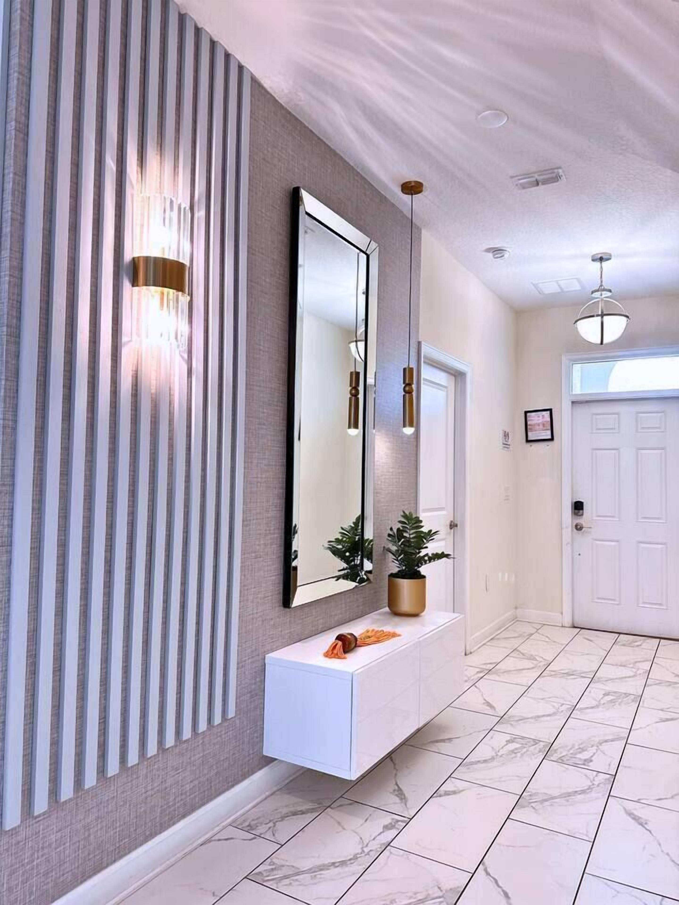A modern hallway with a white console table, a large mirror, and a potted plant.