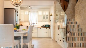 Une cuisine moderne avec des meubles blancs, un coin repas comprenant une table et des chaises, et un escalier menant à un niveau inférieur.