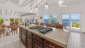 A spacious kitchen with a large island, modern pendant lights, and a view of the ocean. - Private Pool, Sun Deck, Cliffside, Ocean Views, AC (St. Thomas)