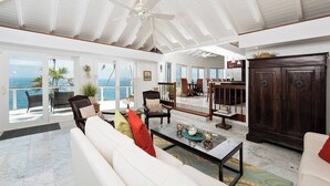 A spacious living area with a high ceiling, large windows, and a view of the sea. - Private Pool, Sun Deck, Cliffside, Ocean Views, AC (St. Thomas)